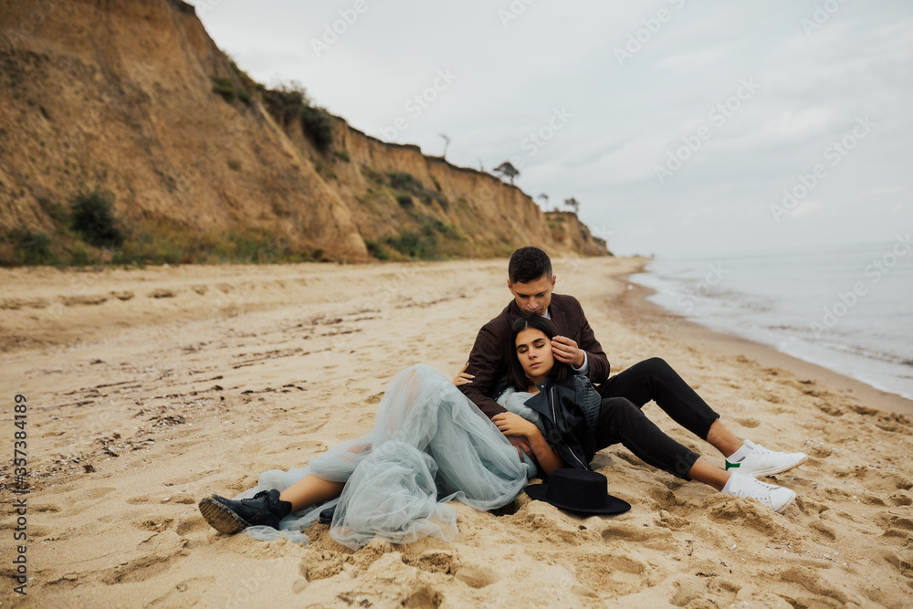 Wedding romance - bride and groom lying on the sand on the beach. Vacation and recreation concept. Wedding couple sit in the beach and kissing against the sea or ocean.  Copy space.