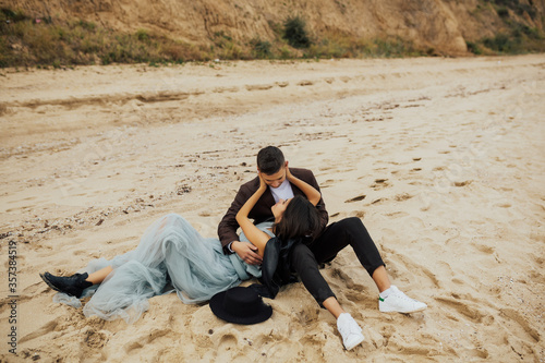 Summer, holidays, vacation and happy people concept - smiling couple lying on the beach. Young happy couple in love lying on the beach, having fun together. Copy space.