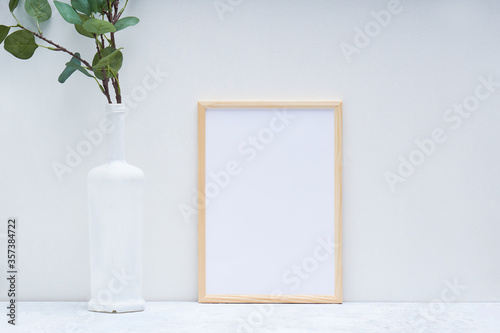 Stylish white mock up with vertical poster and plant in a vase © Natalya
