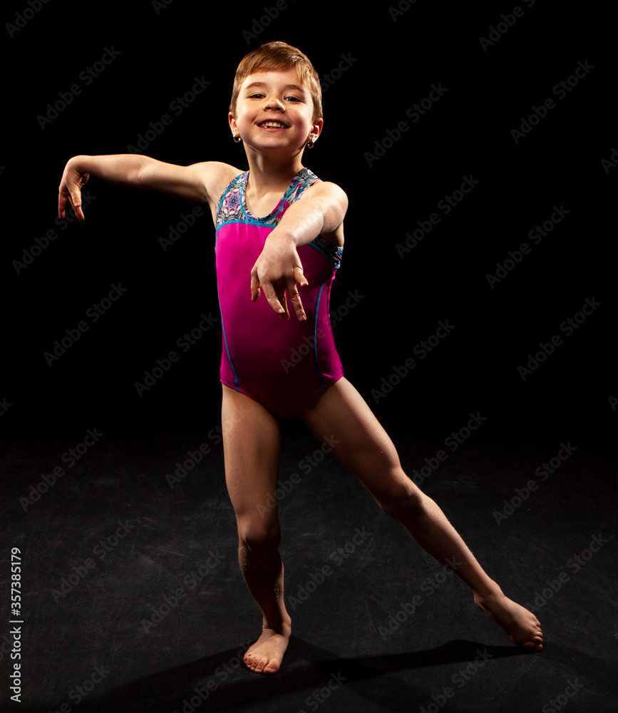 Obraz premium Young gymnast posing on a black background. 