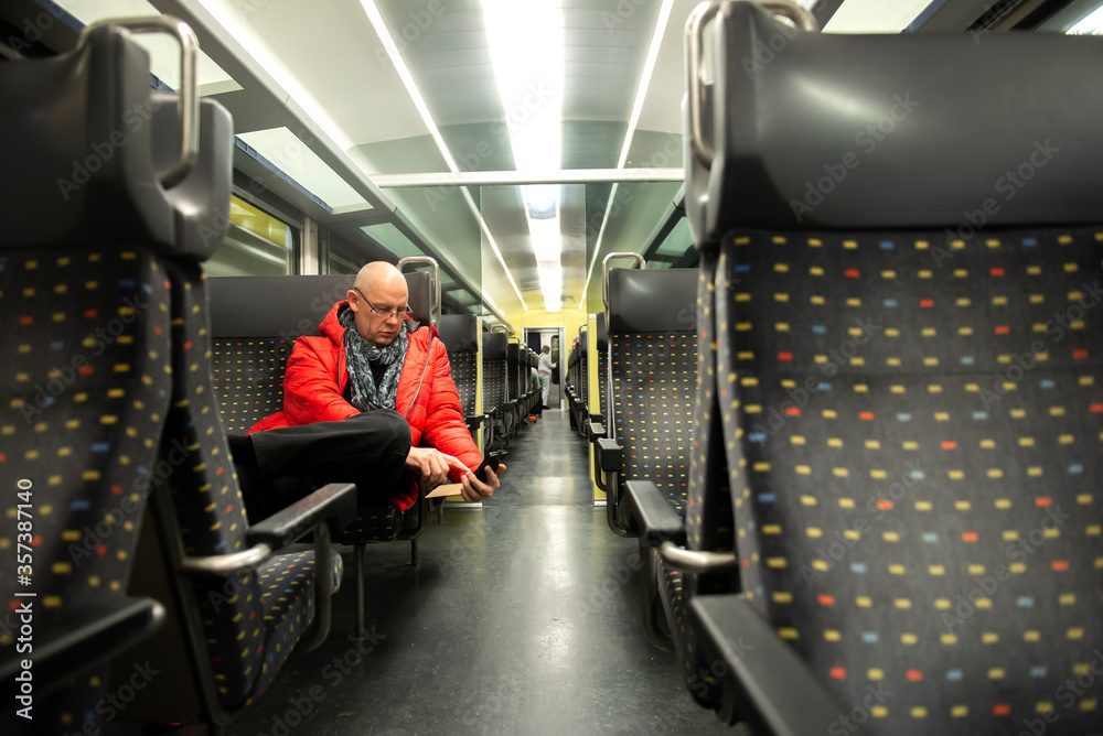 One mature man sits on an empty public transport train and using a cell phone One mature man sits on an empty public transport train and using a cell phone