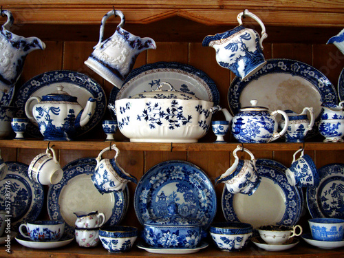 Cottage style kitchen decoration with shelves displaying blue and white British porcelain tea sets.