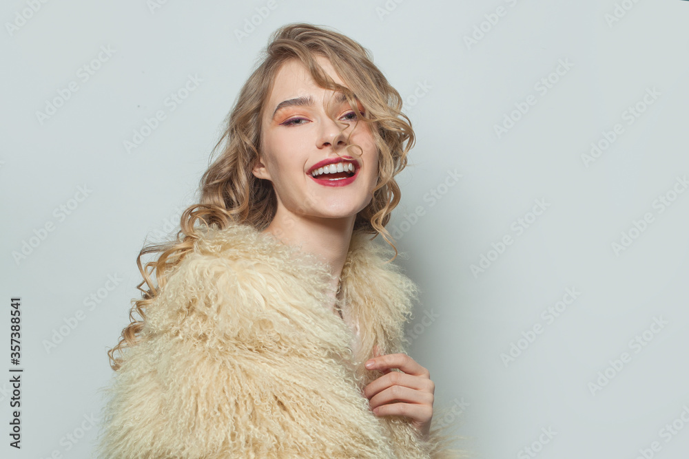 Portrait of laughing woman in eco friendly faux fur coat on white background Portrait of laughing woman in eco friendly faux fur coat on white background