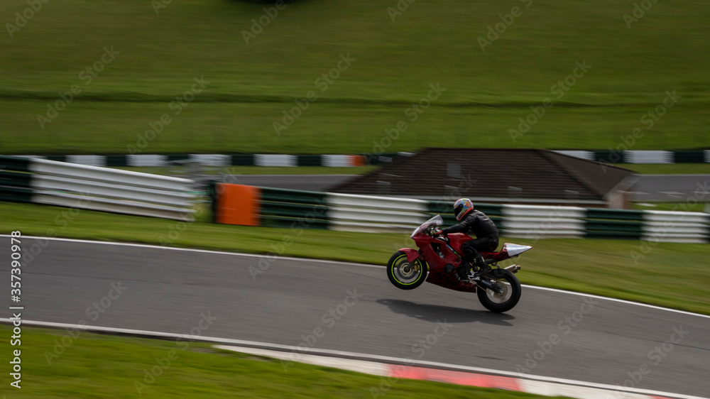 Fototapeta premium A panning shot of a red racing bike on one wheel as it circuits a track