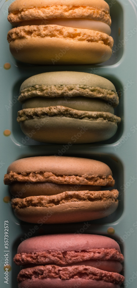 
Detail of four macarons of different colors on a blue support. Aerial view.