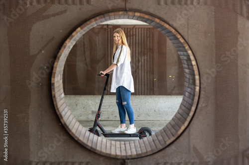 Casual caucasian teenager riding urban electric scooter in urban environment. Urban mobility concept.