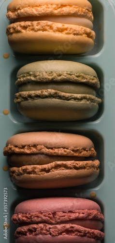  Detail of four macarons of different colors on a blue support. Aerial view.