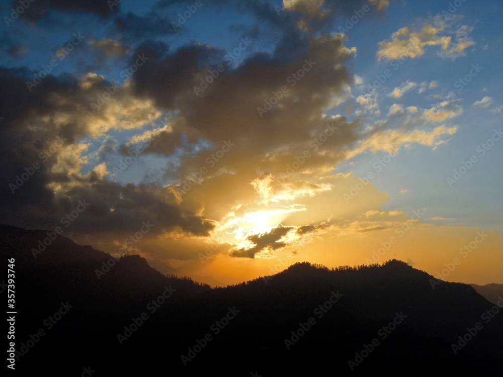 Dawn in the Himalayas. Setting sun hides behind the evening clouds above mountain. Shot near Poon Hill, Nepal