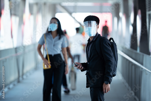 Asian men come to work. They wear a face shield and an anti-virus mask. They are at Skywalk.