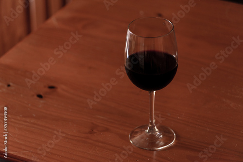 old wicker jerrycan of wine with its bottle and glass of wine on wooden table