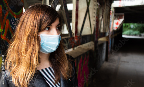 Attractive young woman going for a walk in an industrial area while wearing a face mask during coronavirus outbreak
