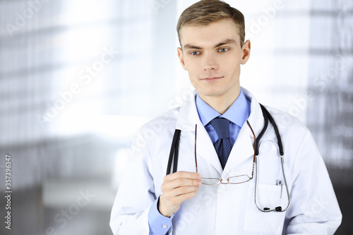 Doctor man  with glasses and stethoscope  is standing at his hospital office. Perfect medical service in clinic. Happy future in medicine and healthcare
