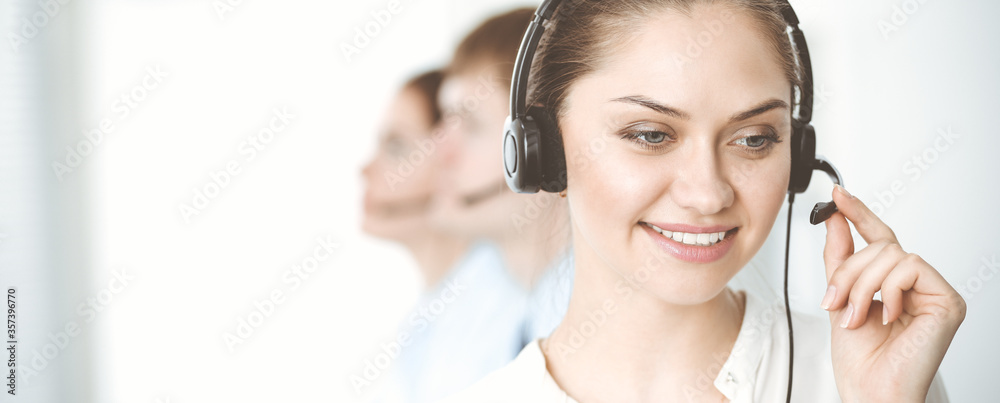 Naklejka premium Call center. Diverse customer service operators in headsets at work in office. Business concept