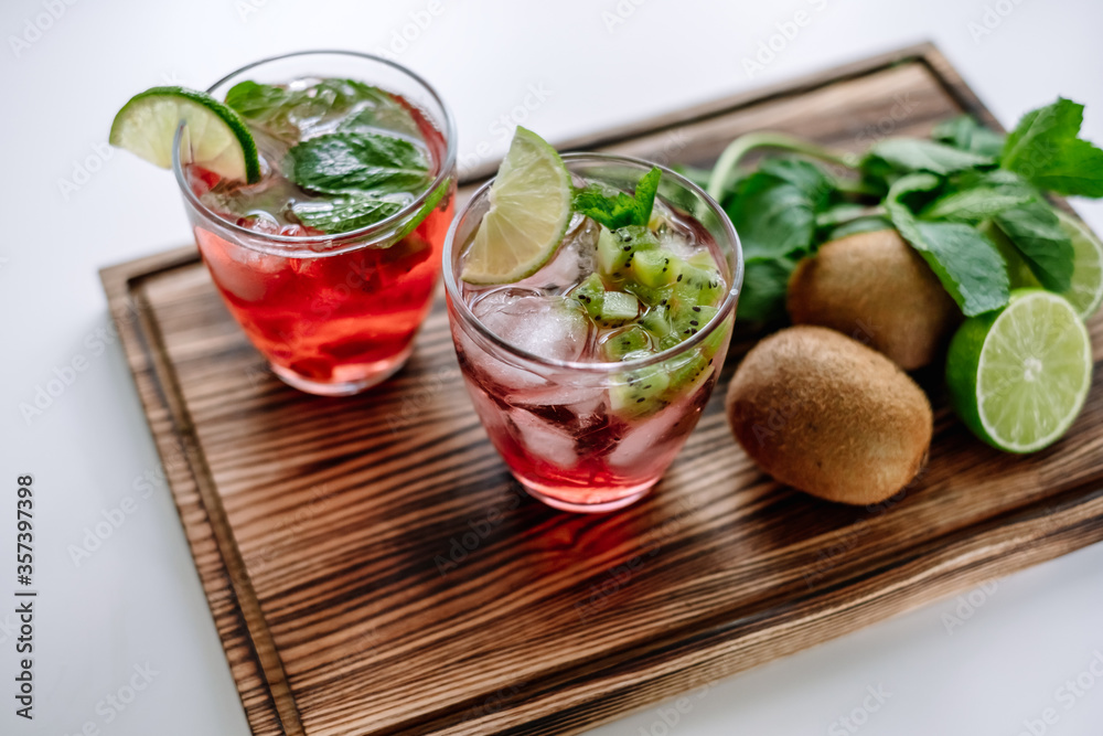 Raspberry cocktail, lemonade with lime, kiwi, mint and pieces of ice on a wooden board. Close-up. Raspberry cocktail, lemonade with lime, kiwi, mint and pieces of ice on a wooden board. Close-up.