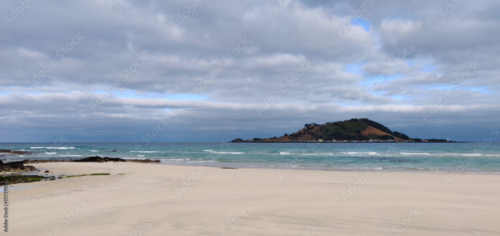 Landscape of Hyeopjae beach with sand, mountain and cobalt blue sea