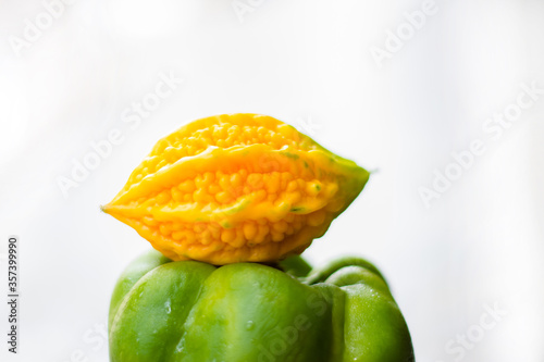 yellow bitter gourd between green capsicum with isolated background  odd one out 