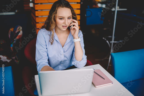 Concentrated female freelance worker making serious telephone conversation with operator