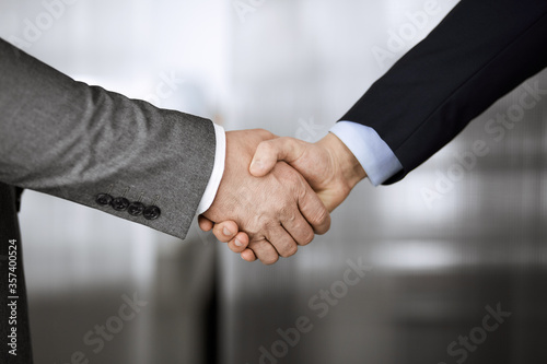 Business people in office suits standing and shaking hands, close-up. Business communication concept. Handshake and marketing © rogerphoto