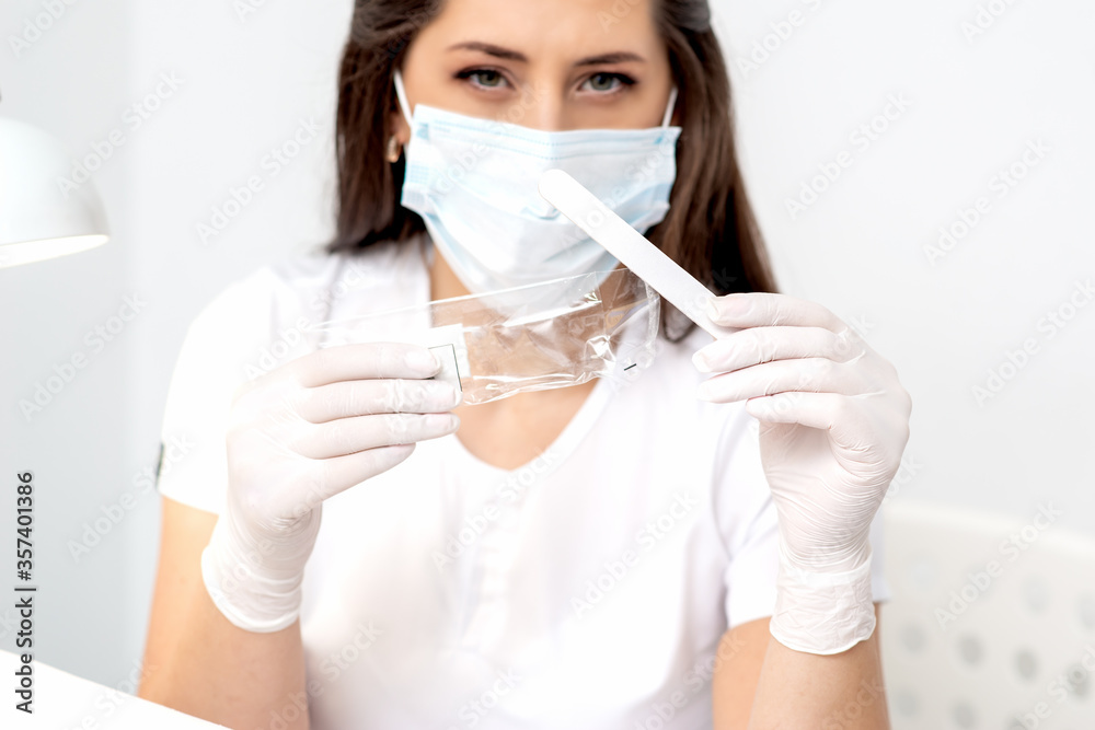 Woman holding medical tool wearing mask in salon. Woman holding medical tool wearing mask in salon.