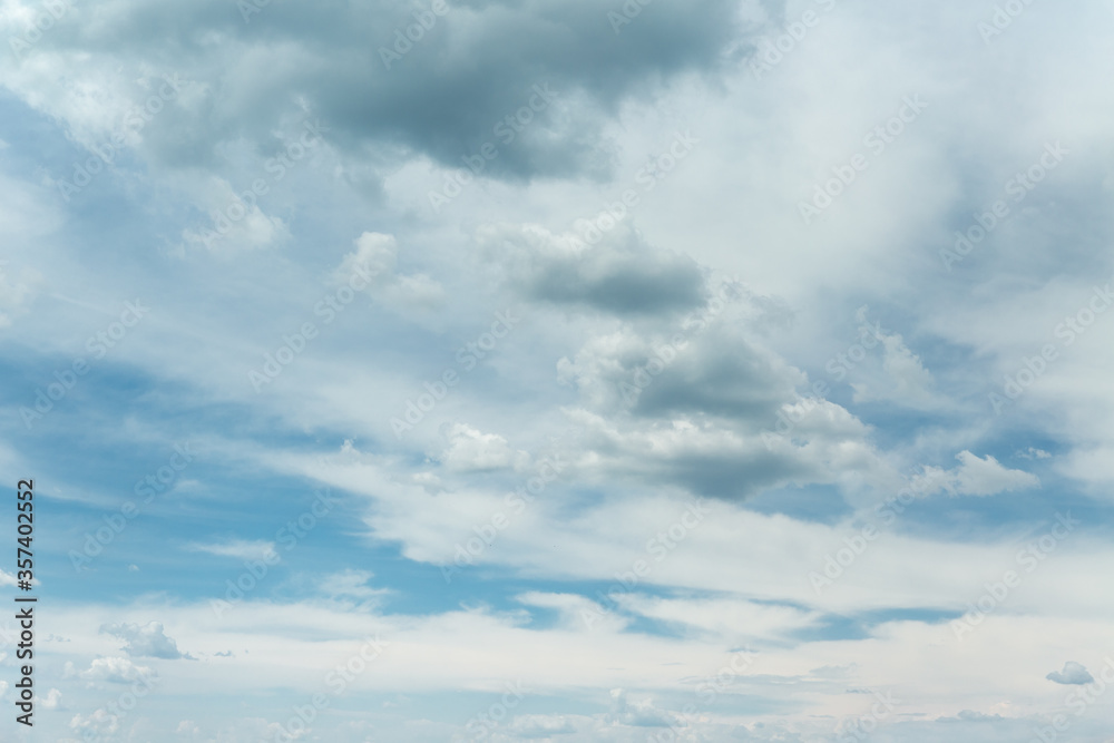 Many white clouds of various shapes in summer sky.