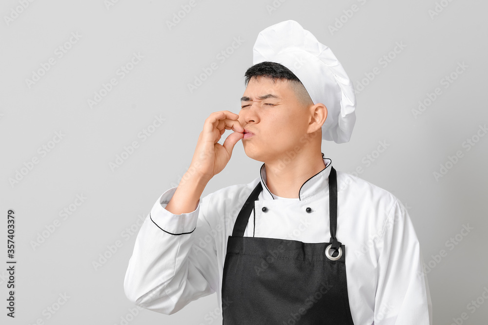Handsome Asian chef on grey background Handsome Asian chef on grey background