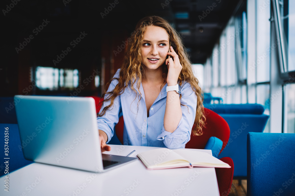Skilled copywriter having mobile conversation while remotely working in cafe Skilled copywriter having mobile conversation while remotely working in cafe