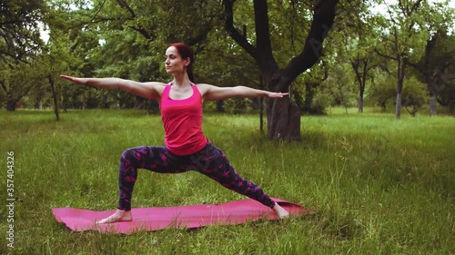 Yoga instructor girl showing Warrior TWO pose, its great for improving blood circulation and respiration stretching outdoors in the park or garden. Prores 422.