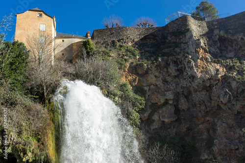 waterfall below old castle in the mountains