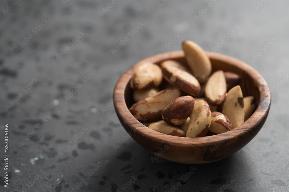 Brazil nuts in olive wood bowl on concrete background with copy space Brazil nuts in olive wood bowl on concrete background with copy space
