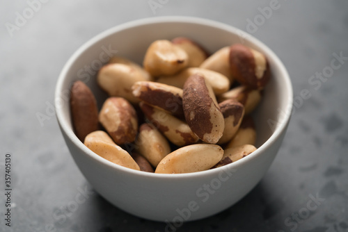 Brazil nuts in white bowl on concrete background closeup