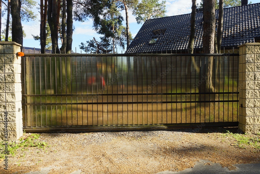 large black closed metal gates and part of a gray stone fence on the street large black closed metal gates and part of a gray stone fence on the street