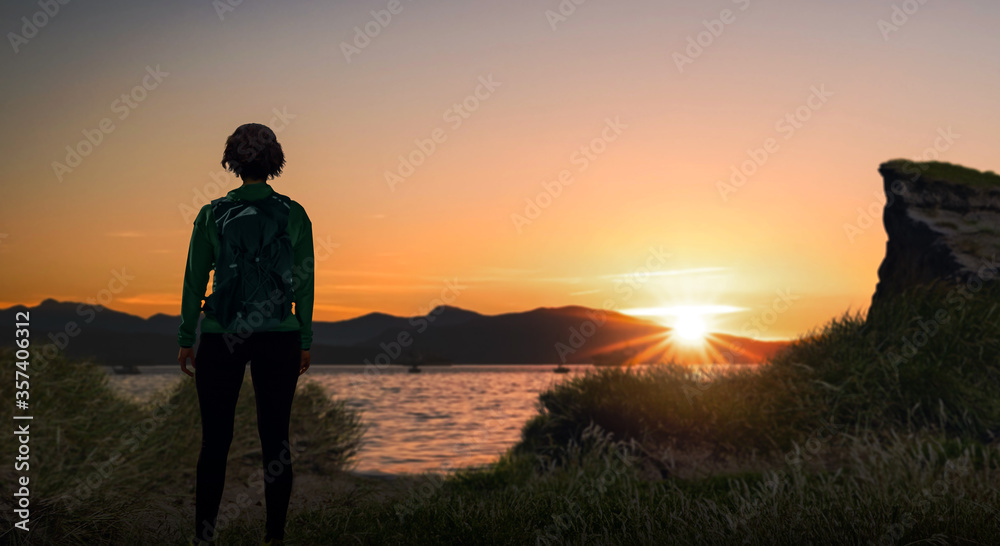 a backpacker girl stand bank of river and enjoy sunset time.