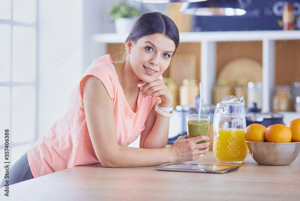 Beautiful young woman using a digital tablet in the kitchen Beautiful young woman using a digital tablet in the kitchen