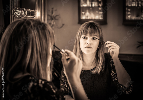 woman looking into a vintage mirror at herself and use cosmetic vanity make up accessories, makeup dressing table