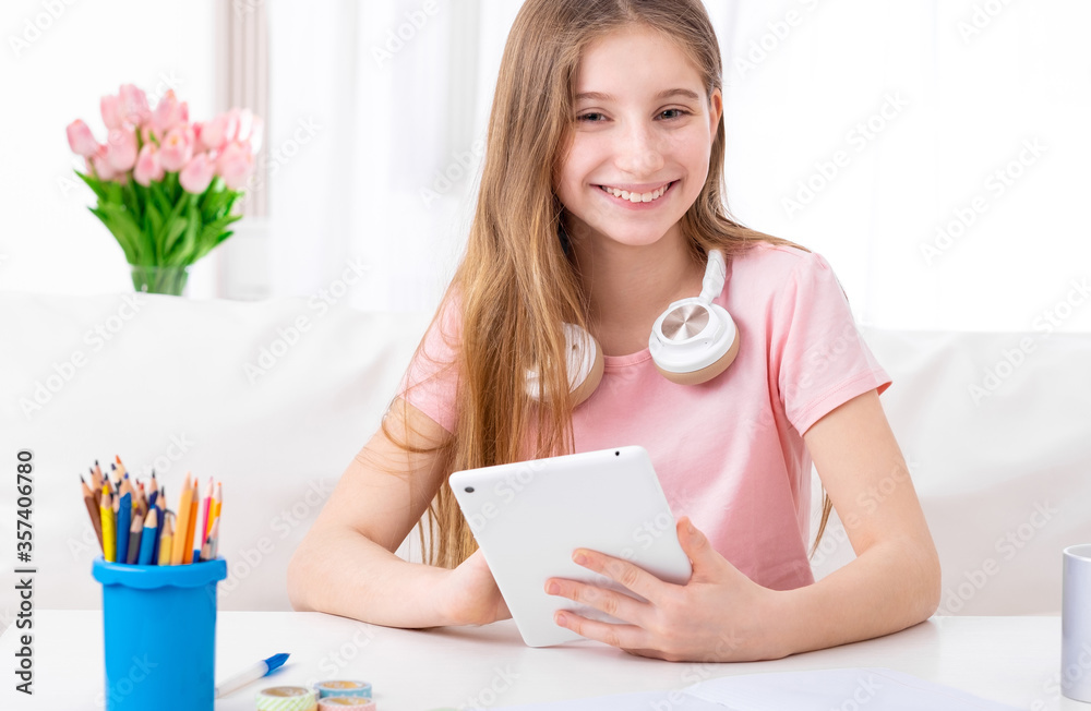 Girl is exploring social networks on her tablet at her working place indoors Girl is exploring social networks on her tablet at her working place indoors