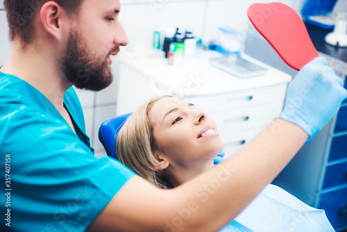 Blond girl and dentist looking into red mirror