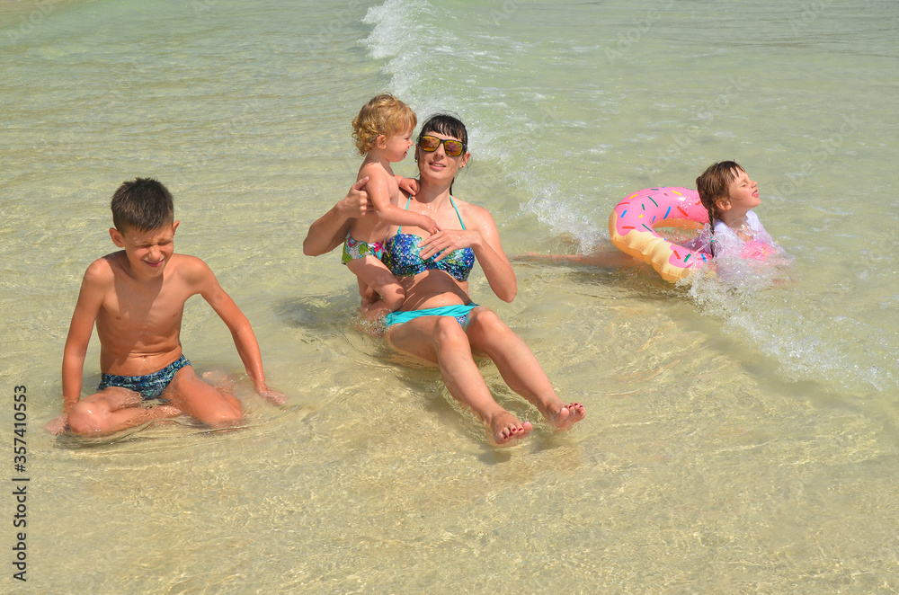 Happy family having fun. Mother and her children swimming in the sea in summer vacation lifestyle Happy family having fun. Mother and her children swimming in the sea in summer vacation lifestyle