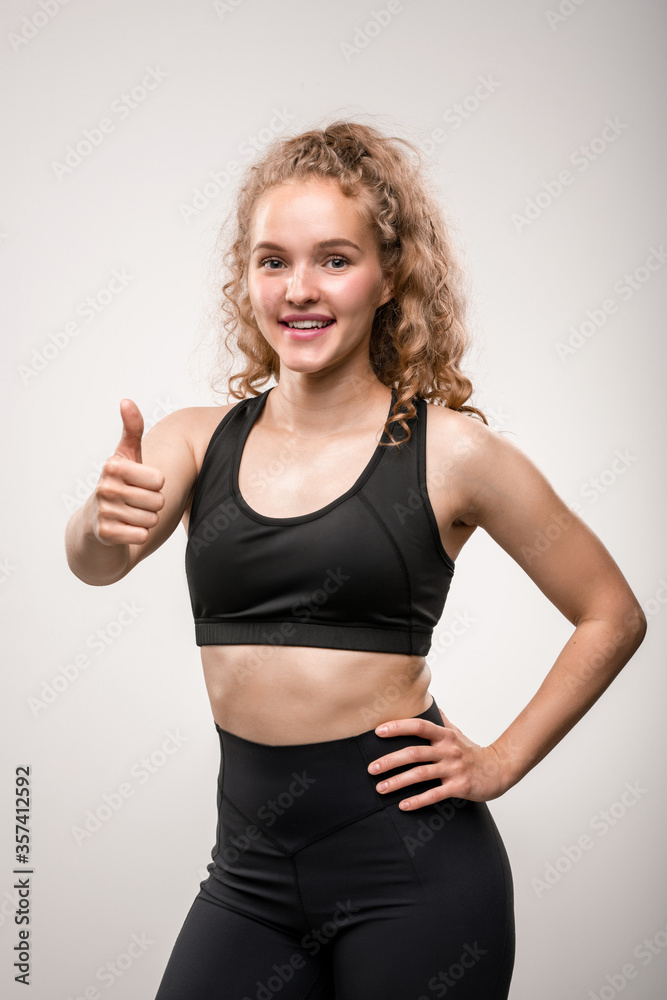 Pretty young fit sportswoman in black tracksuit showing thumb up Pretty young fit sportswoman in black tracksuit showing thumb up