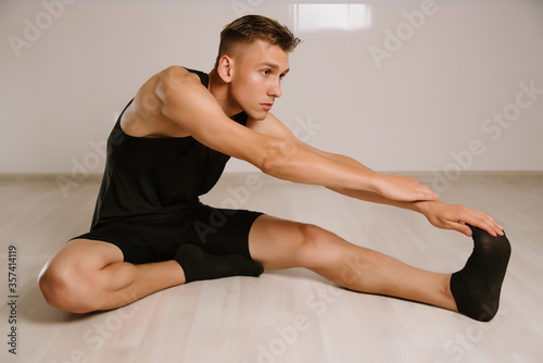 Handsome Young Man Doing Hamstring Stretch Exercise at Home.