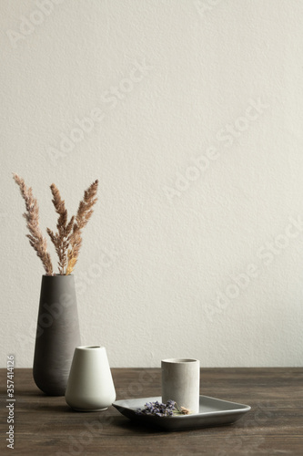 Two white ceramic vases standing on wooden table on background of black one