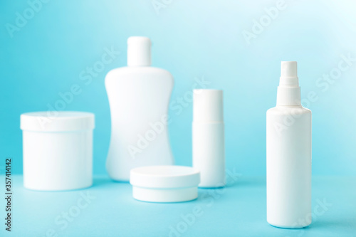 White cosmetic bottles on blue background. Top view