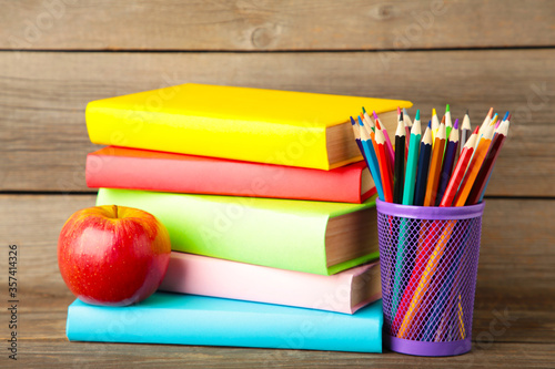 Multi coloured school books and stationery on grey wooden background © Mouse family