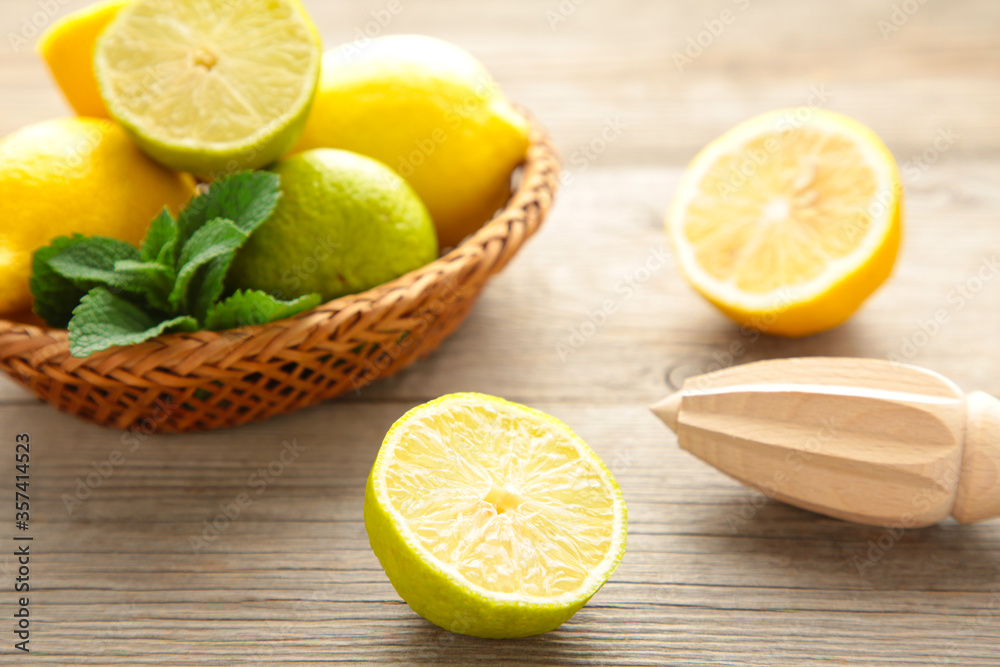 Fresh lime and lemon in basket with citrus juicer stick on grey. Preparation ingredient for cooking with lime and lemon. Fresh lime and lemon in basket with citrus juicer stick on grey. Preparation ingredient for cooking with lime and lemon.