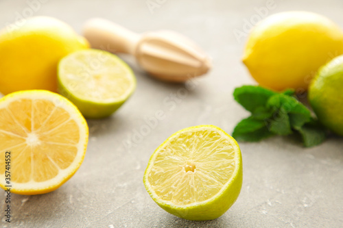 Fresh lime, lemon and mint with citrus juicer stick on grey background. Preparation ingredient for cooking with lime and lemon.