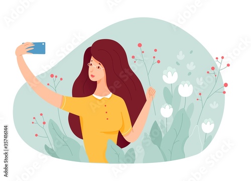 Young girl making selfie in garden with flowering plants