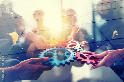 Working group of businessmen find the agreement by holding a piece of gear in hand. concept of teamwork and business partnership. double exposure