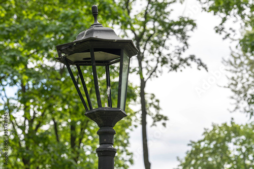 old broken street lamp against the background of summer greenery close up