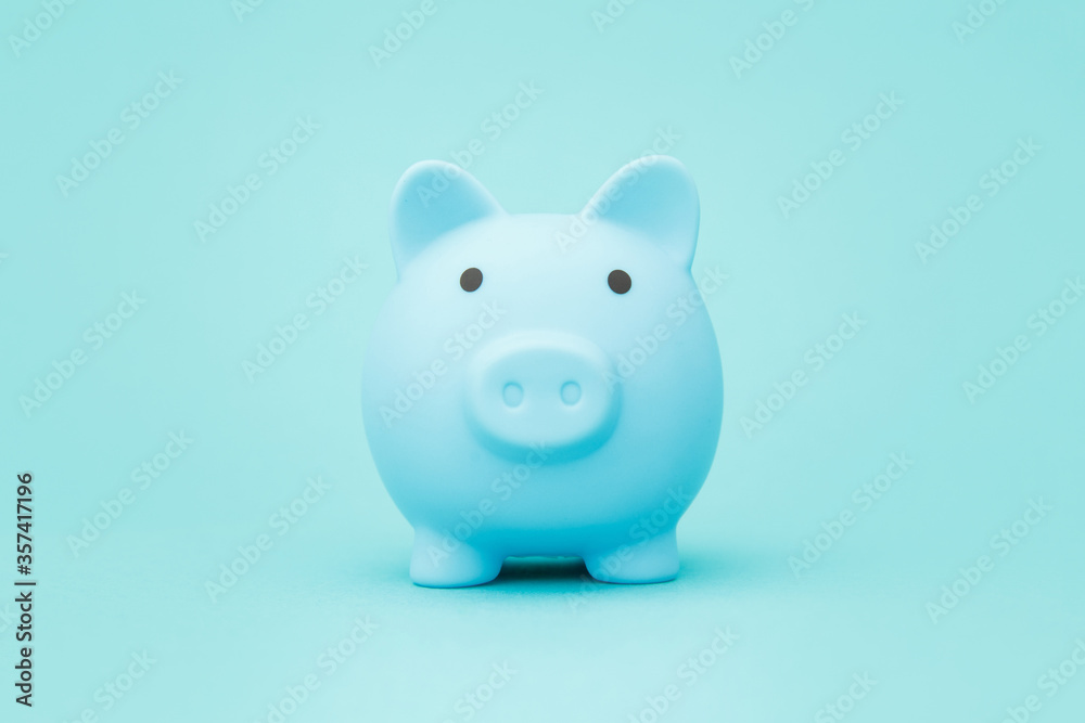 Blue piggy bank on blue background space for text. Savings concept.