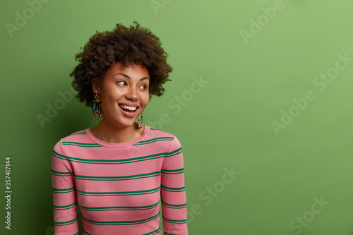 Photos Portrait of positive smiling woman concentrated aside on copy space, has joyful