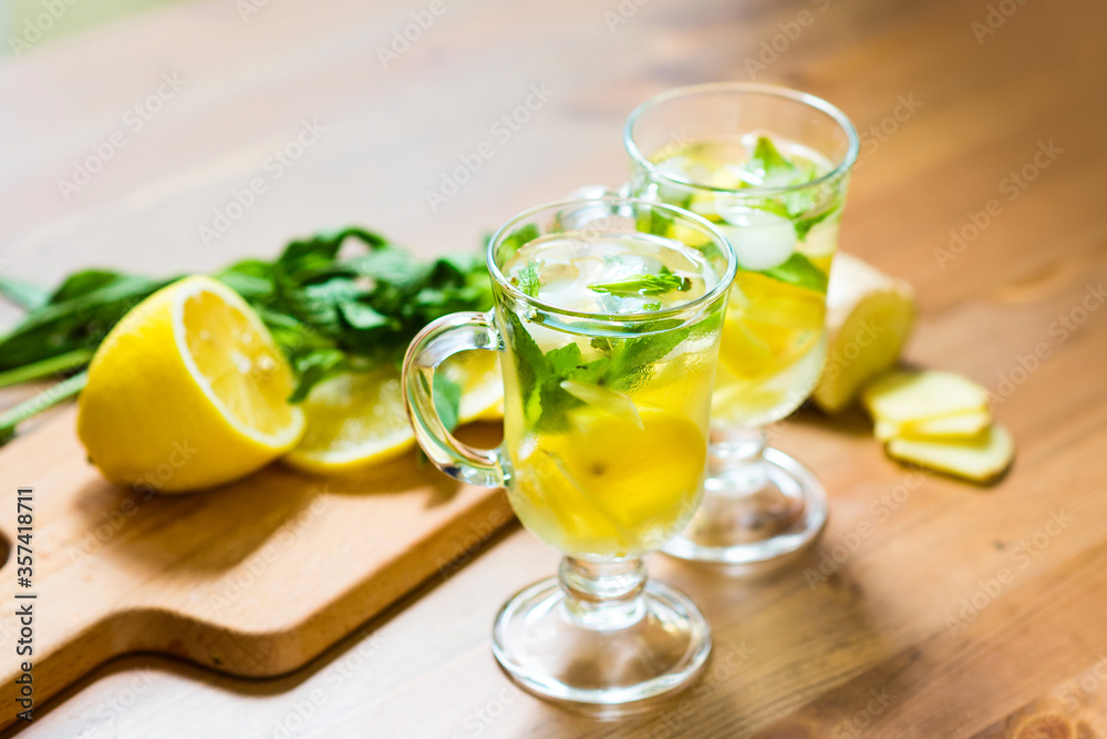 Two glasses with a homemade drink of lemon, mint and ginger